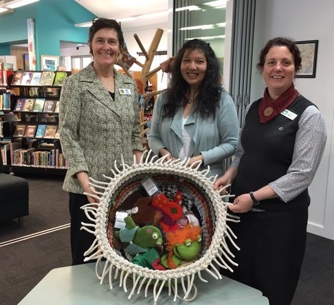 Photo of Cynamon presenting the basket to library staff